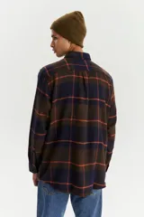 Camisa de franela a cuadros azul marino, marrón y naranja, de corte recto, manga larga, con dos bolsillos frontales con solapa abotonada y cierre frontal con botones.