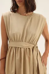 Vestido midi color beige, sin mangas, con lazo en la cintura y bolsillos laterales.