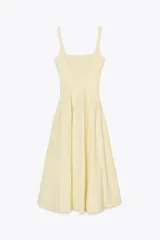 Vestido midi color amarillo pálido con textura arrugada, escote cuadrado, tirantes anchos y falda acampanada.