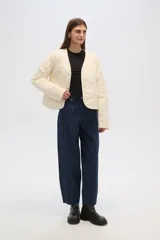 Campera color crema con diseño matelaseado y bordado floral, de corte recto y manga larga.