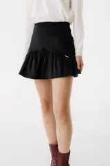 Minifalda negra de corderoy con cintura alta y volado en el ruedo.