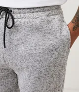 Pantalón de jogging gris oscuro con cintura elástica, cordón de ajuste, bolsillos delanteros y traseros, y tobillos ajustados.