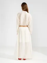 Blusa corta celeste de tejido arrugado liviano, con cuello mao, botones al frente, mangas abullonadas y ruedo elastizado.