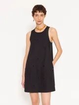Vestido corto negro de poplín con cuello redondo y sin mangas. Presenta apliques de piedras negras en la parte delantera y trasera.