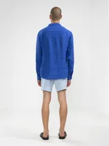 Camisa celeste de lino, de manga larga con botones de coco y parche de la marca.