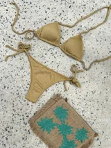 Conjunto de bikini azul con corpiño de triángulos movibles con almohadillas desmontables, que se ata al cuello y a la espalda. La bombacha es vedetina con tiritas a los costados para atar a medida de la cadera.