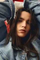 Campera trucker corta de denim celeste, con cuello clásico, cierre frontal con botones metálicos, mangas largas con puños abotonados, bolsillos superiores con solapa y botón, bolsillos laterales y trabillas ajustables con botones en los laterales del bajo.