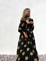 Vestido túnica largo negro con estampado dorado de flores y rayas verticales.