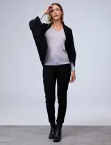 Cardigan negro de tejido suave, estilo poncho o capa, con cuello tipo chal y mangas amplias.
