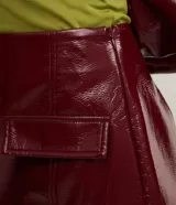 Minifalda color borgoña de cuero sintético con solapas frontales y cierre lateral invisible.