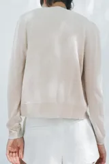 Chaqueta color crema de punto con lana, cuello redondo, manga larga y cierre frontal con botones.