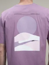 Remera de algodón color azul marino con un estampado gráfico abstracto en la espalda que incluye un círculo azul y formas onduladas en tonos de azul y gris. En la parte superior de la espalda lleva texto impreso.