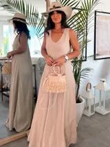 Vestido largo color beige claro, tipo solera, con escote redondo y tirantes anchos. El tejido parece ser crepé o un algodón ligero con textura, de corte amplio y fluido.
