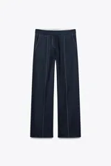 Pantalón de lino color azul marino, de tiro medio, corte recto y bolsillos delanteros y traseros. Presenta pespuntes a contraste en color blanco.