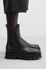 Bota Chelsea de cuero negro con elásticos laterales, tirador trasero y suela track de goma.
