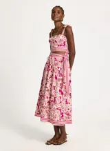 Falda midi con estampado floral en tonos fucsia y beige, con cintura alta y corte acampanado. Presenta una faja a rayas horizontales en la cintura y en el ruedo.