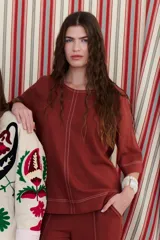 Blusa de lino color beige claro, con mangas 3/4 y cuello redondo. Presenta pespuntes a contratono en el centro, puños y ruedo.