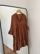 Vestido corto color marrón de fibrana, con cuello mao, tablas en el frente, mangas 3/4 con volados y ruedo con volados.