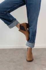 Botín negro de cuero con paneles laterales de gamuza y elástico en los tobillos. Tiene un pequeño taco cuadrado.