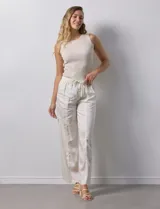 Pantalón palazzo color crudo, marca Nanette, con pretina elastizada, lazo de ajuste y bolsillos delanteros.