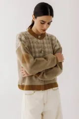Cárdigan marrón con diseño de rombos en tonos rojizos y beige. Tiene cuello redondo, cierre frontal con botones y mangas largas con puños acanalados.