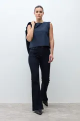 Pantalón de jean oscuro, tiro alto, corte oxford o acampanado, con terminación deshilachada en el ruedo.