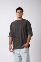 Remera oversize de algodón pesado, color gris oscuro con efecto gastado por lavado snow. Presenta mangas cortas amplias y costuras vistas.