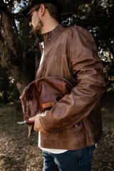 Necessaire de cuero natural marrón confeccionado artesanalmente, con diseño funcional y atemporal. Presenta laterales ajustables, cierre superior metálico y un parche frontal con el logo de la marca Soriame. Interior forrado y reforzado para mayor durabilidad.