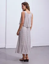 Vestido largo sin mangas, con estampado a rayas verticales en tonos beige, marrón y blanco. Tiene escote redondo y corte a la cintura con punto smock.