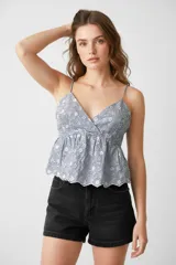 Top de bretel fino con escote en V, estampado a rayas horizontales azules y blancas con bordado de flores blancas.