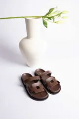 Sandalia plana color beige con dos tiras anchas en el empeine y suela negra.