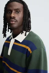 Polo de punto de corte relajado con diseño de rayas horizontales en tonos verde, azul y mostaza. Presenta cuello solapa en color crema a contraste y cierre frontal con tres botones.