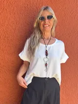 Blusa blanca de seda opaca, corte holgado y mangas cortas con dobladillo.