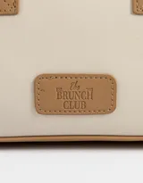 Cartera bowling con estampado de rayas verticales color beige y azul marino. Tiene doble asa corta de mano y correa regulable y desmontable. Incluye cierre superior y tag frontal de cuerina con el logo 'The Brunch Club'.