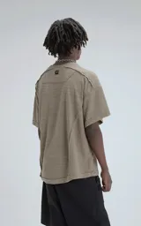 Remera de manga corta y cuello redondo, color verde militar, confeccionada en algodón premium con textura de tejido a rombos. Presenta un calce regular con recortes deshilachados en los hombros.