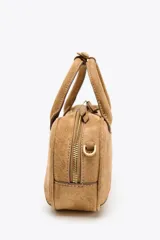 Bolso mini bowling color camel de serraje, con doble asa de mano y correa bandolera extraíble. Tiene un bolsillo interior con cremallera y cierre principal con cremallera y tirador.