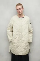 Chaqueta acolchada color beige con patrón de rombos, cuello redondo y cierre con botones a presión.