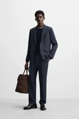 Pantalón de vestir azul marino, de corte recto, con pinzas frontales, bolsillos laterales y traseros de ojal. Se cierra con cremallera y doble botón.
