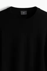 Buzo negro de punto fino suave con cuello redondo y corte slim fit. Presenta ribete acanalado en cuello, puños y bajo.