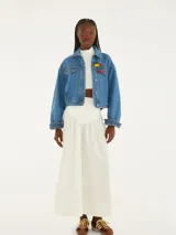 Chaqueta cropped de denim azul con mangas largas y cierre de botones. Tiene bolsillos con solapa y corte recto.
