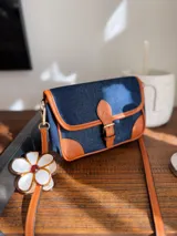 Cartera bandolera de jeans con detalles en cuero color marrón.