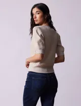Cárdigan tejido color blanco, marca Tahari. Escote en V, manga corta abullonada con puño y abertura central con botones.