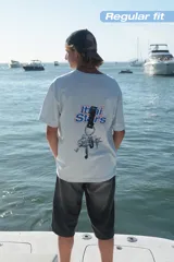 Camiseta celeste con estampado frontal de la frase "Ittai Stars" y una estrella. En la parte posterior tiene un estampado de un llavero con llaves y dijes.