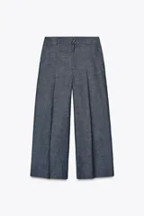 Pantalón culotte azul de lino, tiro alto, con bolsillos delanteros y traseros. Pierna ancha y corta. Cierre frontal con cremallera y botón.