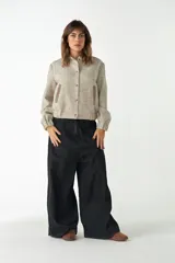 Campera estilo bomber de cuello redondo, color beige jaspeado, con cierre frontal de broches y bolsillos delanteros con ribete marrón.