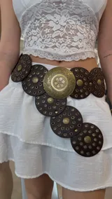 Cinturón de cuero marrón con apliques circulares de metal dorado y diseño calado.