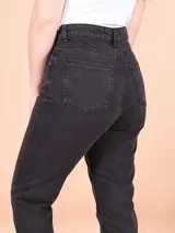Pantalón jean negro de tiro alto, corte recto y largo al tobillo. Diseño clásico con bolsillos delanteros y traseros.
