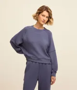 Buzo deportivo femenino confeccionado en microfibra color azul, con cuello redondo, mangas raglán largas y recortes.