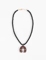 Collar con cordón negro y dije de herradura marrón con apliques dorados.
