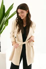 Trench simil gamuza color marrón, con cuello de solapa muesca, cuatro botones delanteros, bolsillos laterales y cinturón a la altura de la cintura.